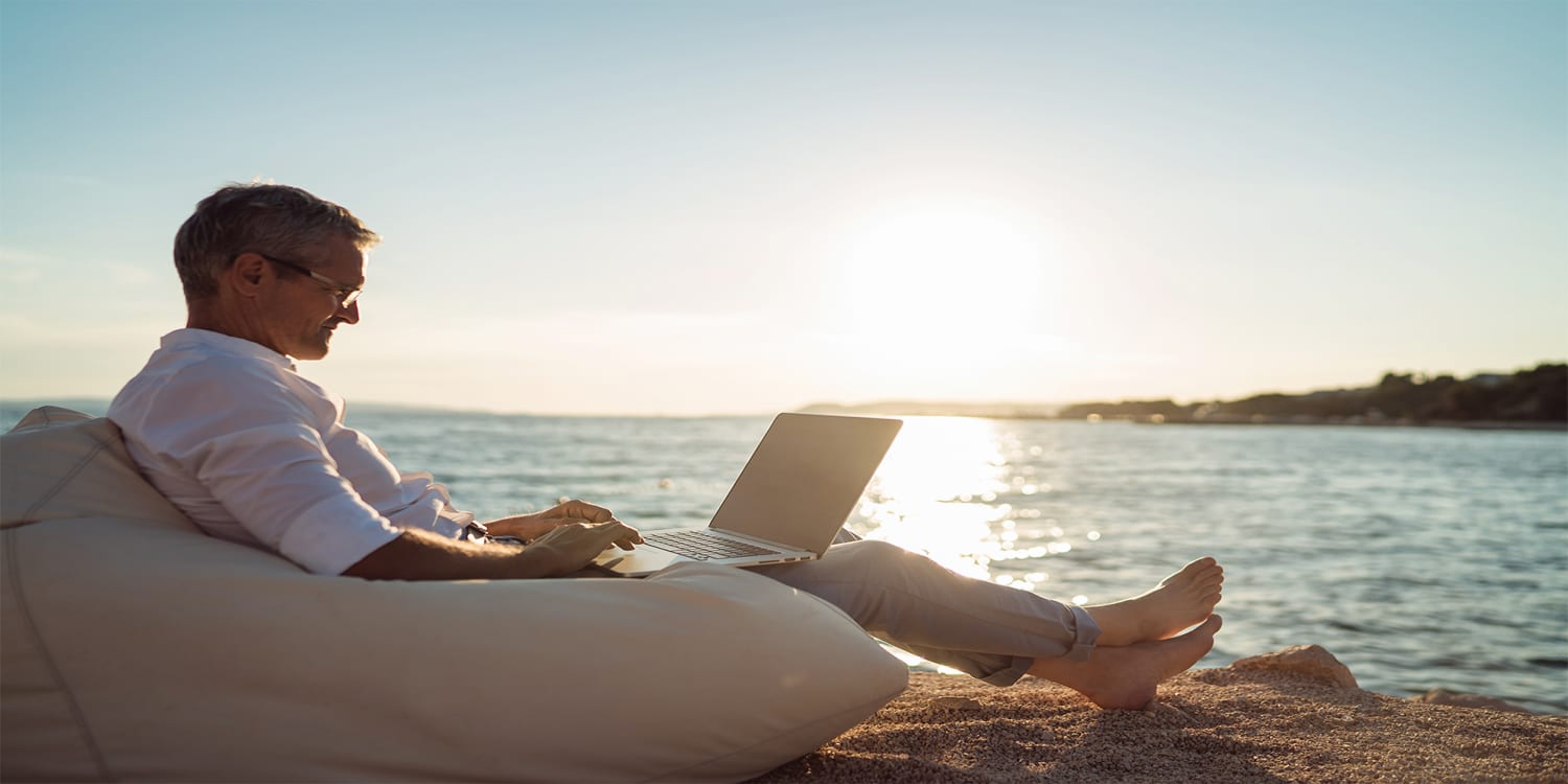 Real estate investor sitting on beach looking at investment portfolio
